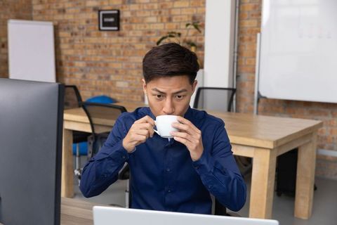 Businessman Drinking Coffee While Working Indoors at Modern Workspace