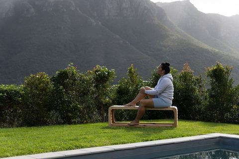 Woman Sitting on Wooden Bench Beside Pool Overlooking Mountain Range, Backyard Serenity