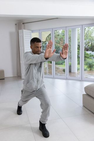 Man Practicing Martial Art Poses in Modern Living Room
