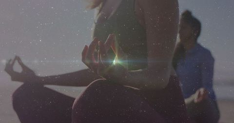 Sunlit beach yoga meditation duo practicing gyan mudra for mindfulness and calm