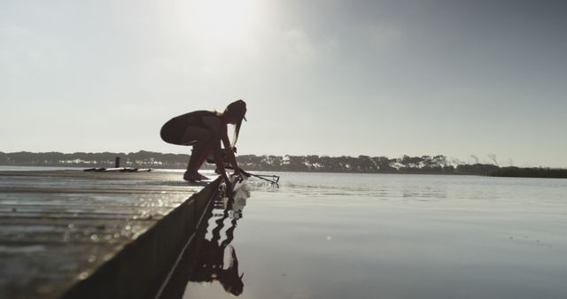 Silhouette of Canoeist Preparing on Lakeshore at Dawn - Download Free Stock Images Pikwizard.com