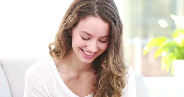 Smiling Young Woman Looking Down Indoors with Natural Sunlight - Download Free Stock Images Pikwizard.com