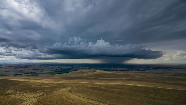 Dramatic Supercell Storm Dumping Heavy Rain Over Rolling Prairie Hills and Farmland