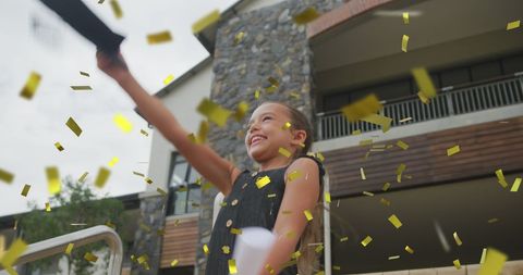 Joyful Schoolgirl Celebrating Graduation with Gold Confetti