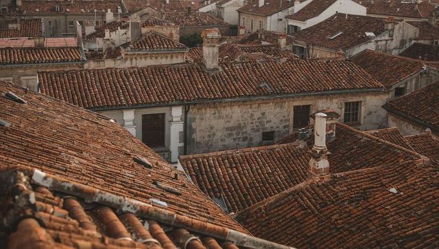 Aerial view of terracotta clay-tiled rooftops and chimneys in historic Mediterranean town