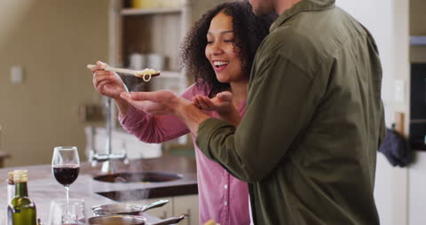 Happy Couple Tasting Spaghetti While Cooking at Home