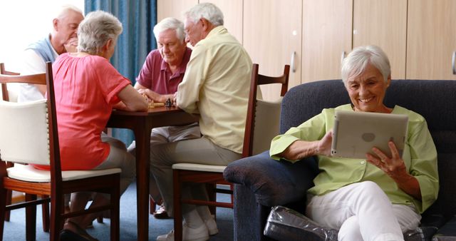 Retirees Playing Board Games While Woman Using Digital Tablet in Retirement Home - Download Free Stock Images Pikwizard.com