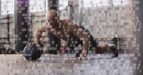 Shirtless athlete balancing on medicine ball performing plank with binary digital overlay