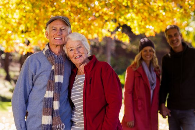 Portrait of happy family standing at park during autumn