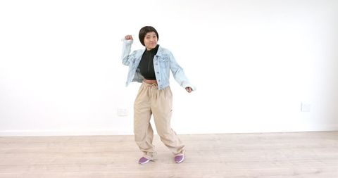 Young Woman Dancing Happily in Casual Attire on Wood Floor