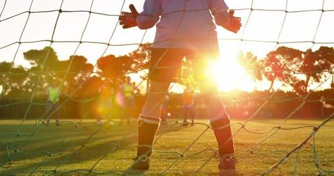 Goalkeeper training at sunset on soccer field