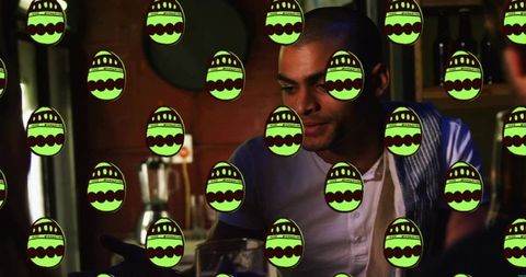 Man sitting and working behind dimly lit bar with neon green egg pattern overlay