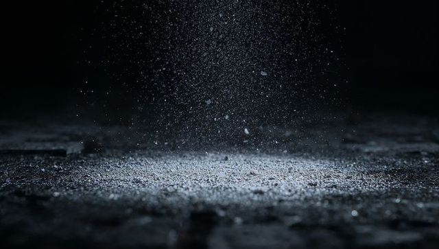 Falling powder and suspended dust spotlighting rough concrete floor moody dramatic texture