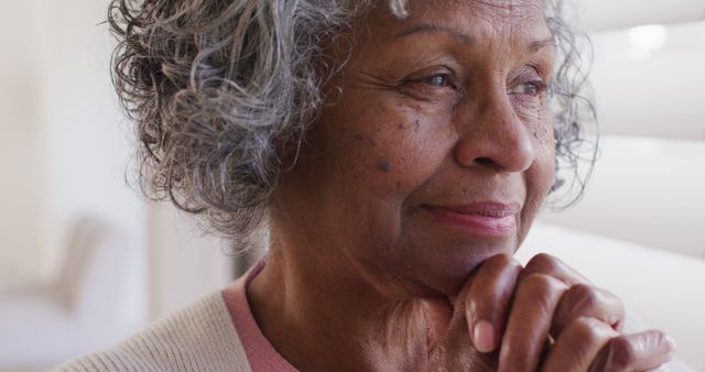 Happy senior african american woman looking through window. Retirement and spending time at home concept.