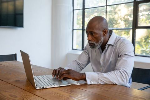 Mature professional man working on laptop in modern office