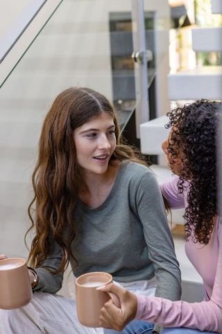 Diverse Female Friends Having Coffee on Modern Staircase