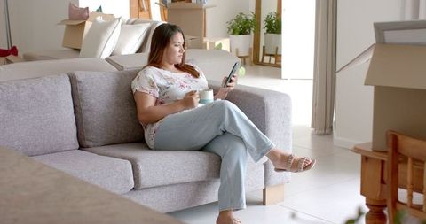 Woman in New Home Relaxing with Smartphone and Coffee