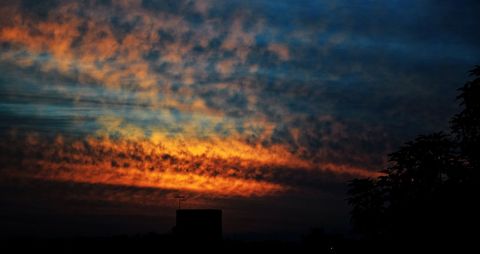 Vibrant Sunset with Silhouetted Urban Roofline and Clouds