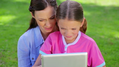 Mother and Daughter Enjoying Tablet Time in Park