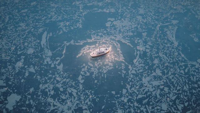 Aerial solitary motorboat navigating fractured sea ice under soft halo of light at dusk
