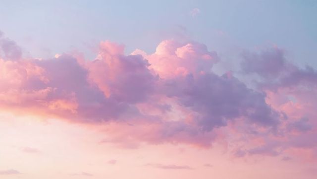Pastel dawn cumulus cloudscape glowing in pink lavender peach light over serene horizon