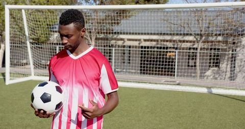 Athlete Holding Soccer Ball on Training Field Near Goal