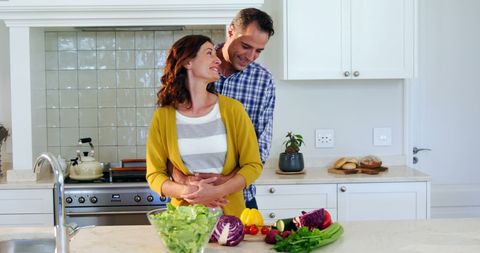 Happy Couple Embracing in Kitchen with Fresh Vegetables