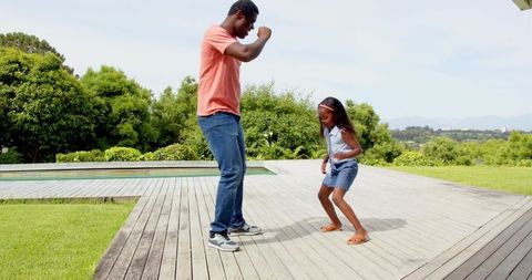 Father and Daughter Joyfully Dancing by Poolside Deck