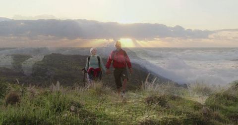 Senior Couple Hiking Coastal Trail at Sunset with Trekking Gear