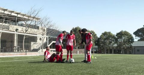 Coach instructing young soccer players during practice on field