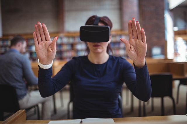 Mature student immersed in virtual reality using a VR headset in a college library. Ideal for use in educational technology articles, college promotions, virtual learning demonstrations, and future of education presentations.