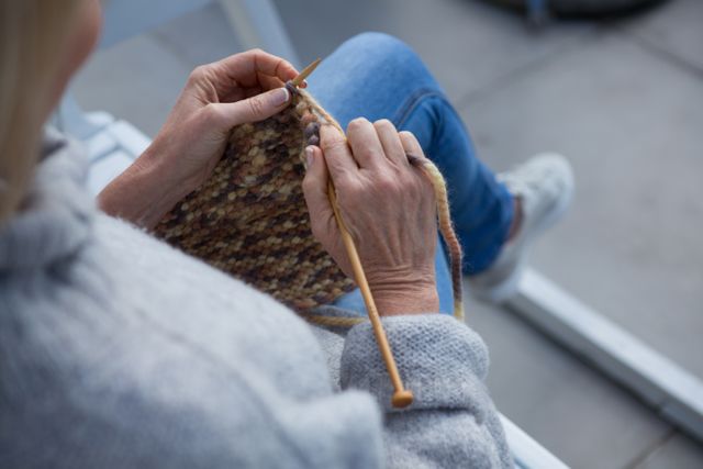 Overhead of woman knitting wool in porch