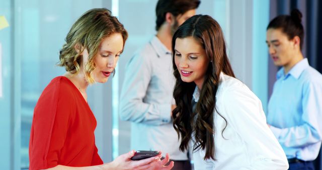 Two Businesswomen Discussing Work on Smartphone in Modern Office - Download Free Stock Images Pikwizard.com