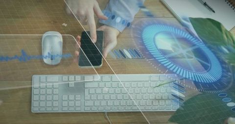 Hands tapping smartphone on desktop keyboard with futuristic hud interface and data visualization