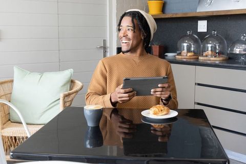 Young african american man enjoying coffee while using tablet in cozy cafe