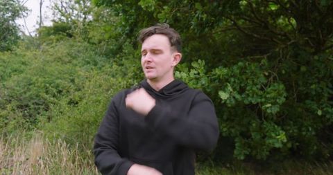 Man stretching arms outdoors in nature before running
