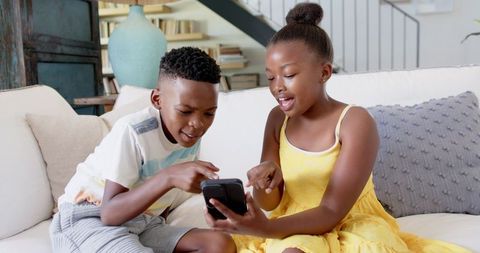 Siblings Engaged with Smartphone Together in Living Room