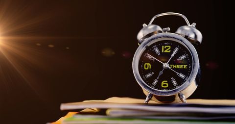 Alarm clock on books symbolizing time for reading and learning