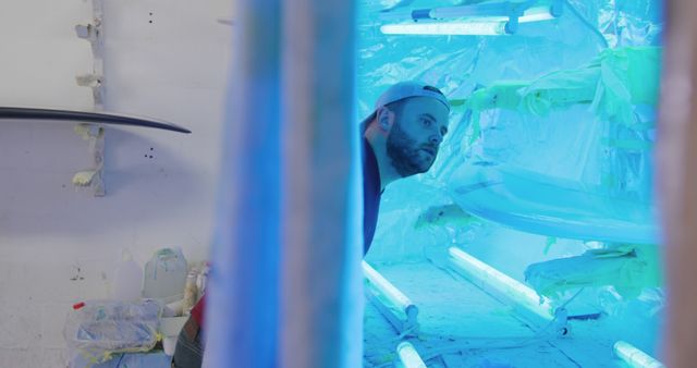 Male Technician Inspecting Surfboards in Ultraviolet Light Room - Download Free Stock Images Pikwizard.com