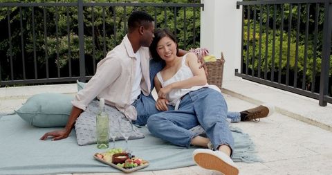 Happy couple on terrace picnic enjoying fruit and drinks