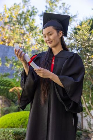 Young graduate celebrating success holding diploma outdoor