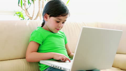 Little Girl Engaged with Laptop on Comfortable Sofa