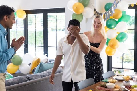 Friends Surprising Man Covering Eyes at Fun Birthday Gathering