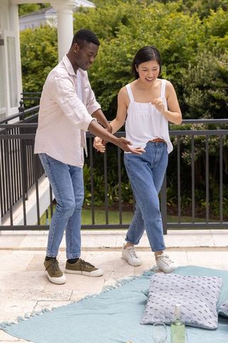 Asian woman and african american man practicing dance steps on patio enjoying casual outdoor time