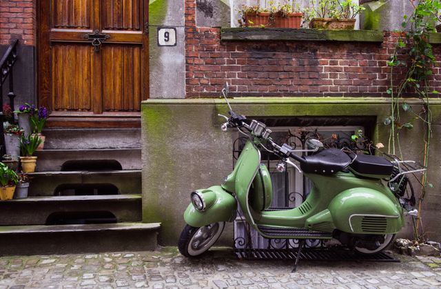 Retro Green Scooter Parked by Rustic Brick House on Cobblestone Street - Download Free Stock Images Pikwizard.com