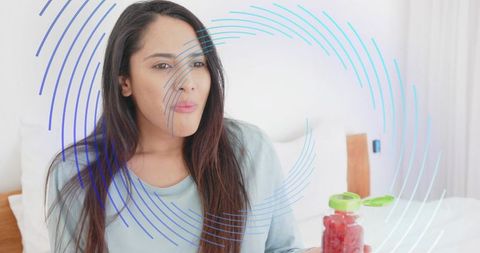 Indian woman presenting jar of jam on bed holding spoon modern cozy wellness lifestyle