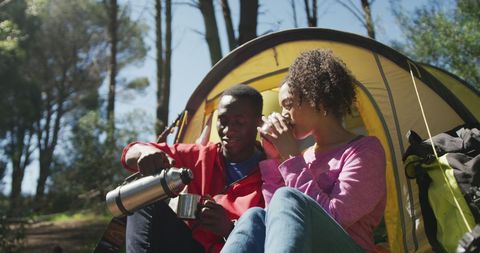 Relaxed Couple Enjoying Hot Drinks Inside Forest Tent