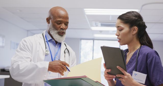 Diverse male and female doctors holding clipboard and tablet, talking at hospital - Download Free Stock Photos Pikwizard.com