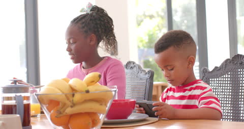 Siblings Enjoying Breakfast and Using Smartphone Together