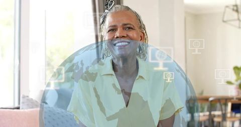 Smiling senior woman using virtual tech at home with globe overlay and bright interior